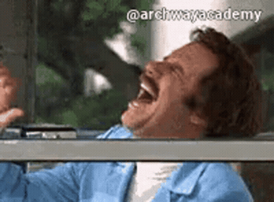 A Man With A Mustache Is Laughing With His Mouth Open While Sitting In A Car . GIF