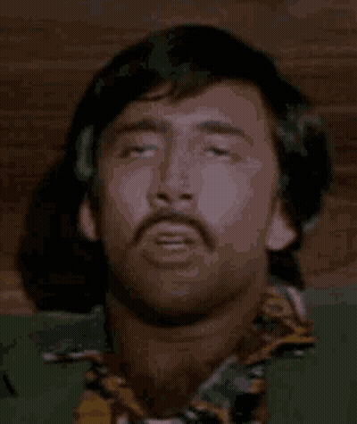 A Man With A Mustache Is Laying Down With His Eyes Closed And His Head Is Visible . GIF