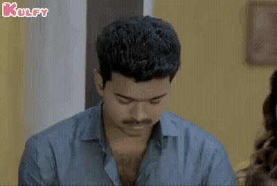 A Man With A Mustache Is Looking Down At Something While Sitting At A Table With A Woman . GIF