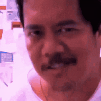 A Man With A Mustache Is Making A Funny Face While Looking At The Camera . GIF