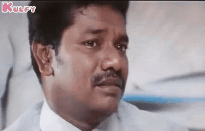 A Man With A Mustache Is Making A Funny Face While Sitting In A Chair . GIF