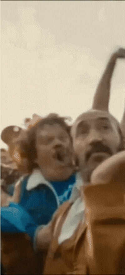 A Man With A Mustache Is Making A Funny Face While Sitting Next To Another Man GIF
