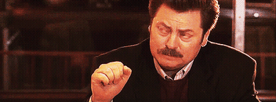 A Man With A Mustache Is Making A Funny Face With His Fist In The Air . GIF