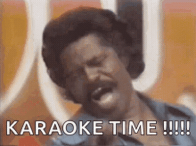 A Man With A Mustache Is Singing Into A Microphone With The Words `` Karaoke Time !!! '' Written Below Him . GIF