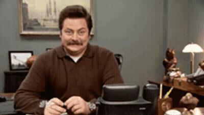 A Man With A Mustache Is Sitting At A Desk GIF