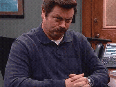 A Man With A Mustache Is Sitting At A Desk With His Hands Folded And A Watch On His Wrist . GIF