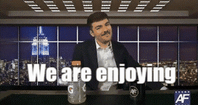 A Man With A Mustache Is Sitting At A Table With The Words " We Are Enjoying " Above Him GIF