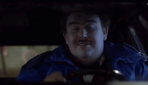 A Man With A Mustache Is Sitting In A Car Smoking A Pipe . GIF
