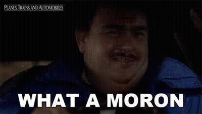 A Man With A Mustache Is Sitting In A Car With The Words What A Moron Below Him GIF
