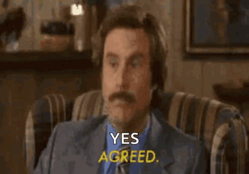 A Man With A Mustache Is Sitting In A Chair With His Eyes Closed And Says Yes Agreed . GIF