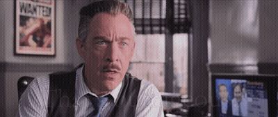 A Man With A Mustache Is Sitting In Front Of A Poster That Says Wanted GIF
