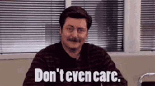 A Man With A Mustache Is Sitting In Front Of A Window With Blinds And Says `` Don 'T Even Care '' . GIF