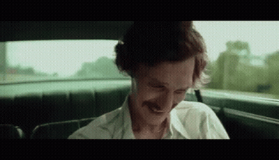 A Man With A Mustache Is Sitting In The Back Seat Of A Car Smiling . GIF