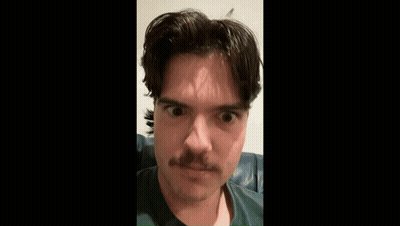 A Man With A Mustache Is Sitting On A Couch . GIF