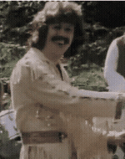 A Man With A Mustache Is Smiling And Holding A Glass Of Wine GIF