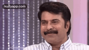 A Man With A Mustache Is Smiling And Looking At The Camera . GIF