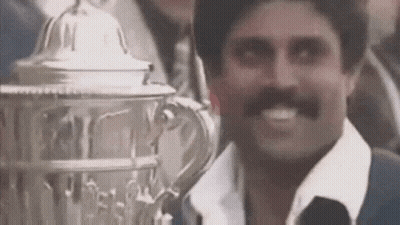 A Man With A Mustache Is Smiling While Holding A Trophy In Front Of Him . GIF