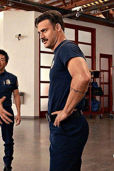 A Man With A Mustache Is Standing In A Room With His Hands On His Hips And Another Man Standing Behind Him . GIF