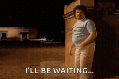 A Man With A Mustache Is Standing In Front Of A Building And Saying I 'Ll Be Waiting GIF