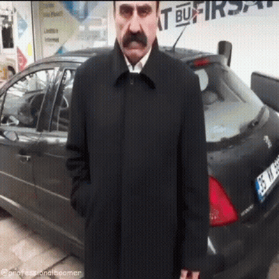 A Man With A Mustache Is Standing In Front Of A Car That Has A License Plate That Starts With Gs GIF