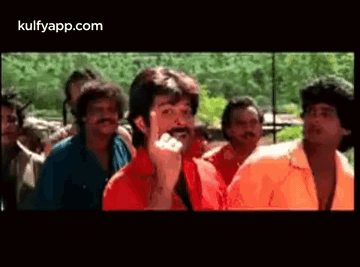 A Man With A Mustache Is Standing In Front Of A Crowd Of Men . GIF
