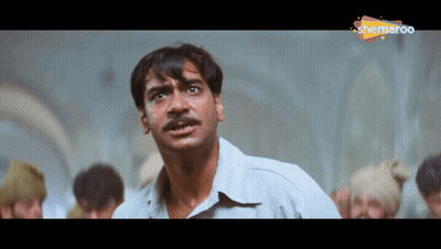 A Man With A Mustache Is Standing In Front Of A Group Of People And A Sign That Says Shemaroo On It GIF