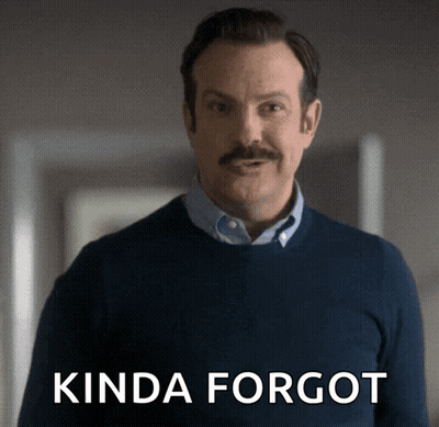 A Man With A Mustache Is Standing In Front Of A Sign That Says " Kinda Forgot " GIF