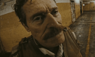 A Man With A Mustache Is Standing In Front Of A Yellow Wall GIF