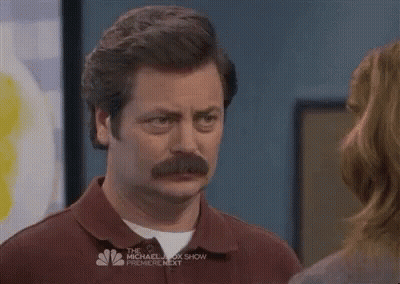A Man With A Mustache Is Standing Next To A Woman And Looking At Her . GIF