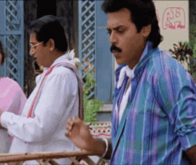 A Man With A Mustache Is Standing Next To Another Man In A Colorful Shirt . GIF
