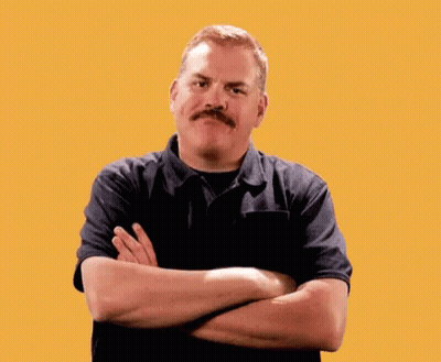 A Man With A Mustache Is Standing With His Arms Crossed In Front Of A Yellow Background GIF