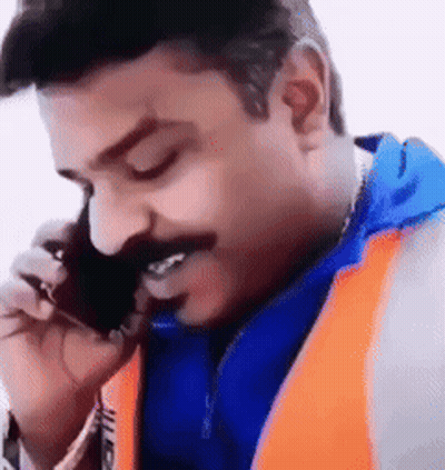 A Man With A Mustache Is Talking On A Cell Phone And Smiling . GIF