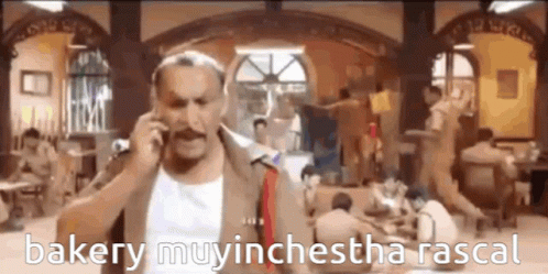 A Man With A Mustache Is Talking On A Cell Phone In A Room . GIF