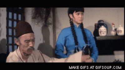A Man With A Mustache Is Talking To A Woman In A Blue Shirt GIF