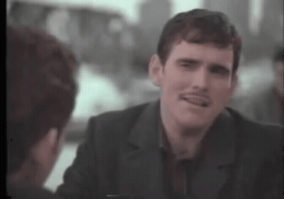 A Man With A Mustache Is Talking To Another Man In A Suit . GIF