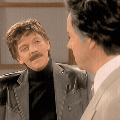 A Man With A Mustache Is Talking To Another Man GIF