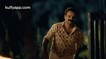 Man With Mustache Waving In Front Of Gate GIF