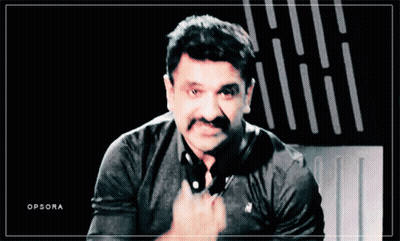 A Man With A Mustache Is Wearing A Black Polo Shirt With A White Horse On It GIF