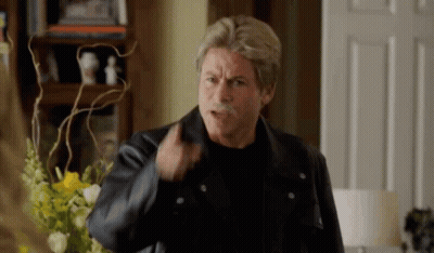 A Man With A Mustache Is Wearing A Leather Jacket And A Black Shirt . GIF