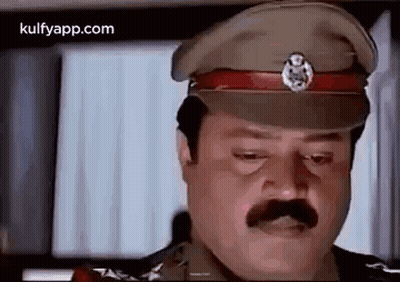 A Man With A Mustache Is Wearing A Military Hat And Looking Down . GIF