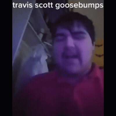 A Man With A Mustache Is Wearing A Red Shirt And Has The Name Travis Scott Goosebumps On His Face GIF