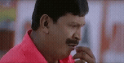A Man With A Mustache Is Wearing A Red Shirt And Looking At Something . GIF