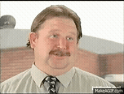 A Man With A Mustache Is Wearing A Shirt And Tie And Looking At The Camera . GIF