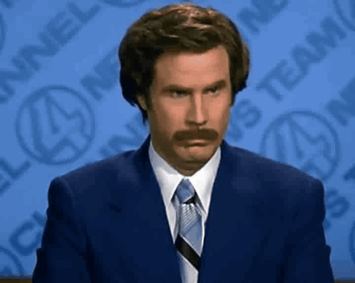 A Man With A Mustache Is Wearing A Suit And Tie GIF