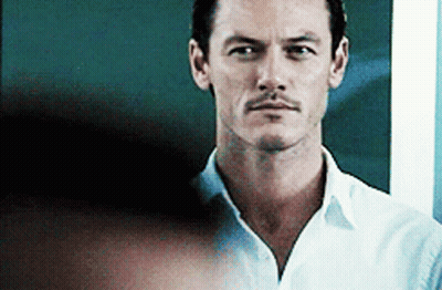 A Man With A Mustache Is Wearing A White Shirt And Looking At The Camera With A Serious Look On His Face . GIF