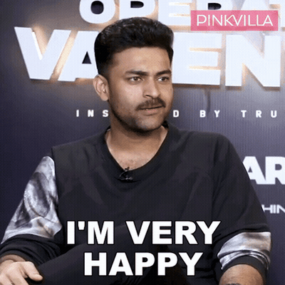 A Man With A Mustache Says I 'M Very Happy In Front Of A Pinkvilla Sign GIF