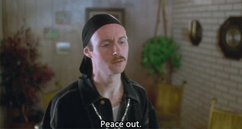 A Man With A Mustache Says Peace Out In A Room GIF