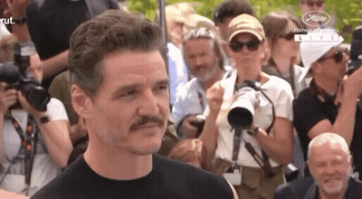 A Man With A Mustache Stands In Front Of A Crowd Of People . GIF