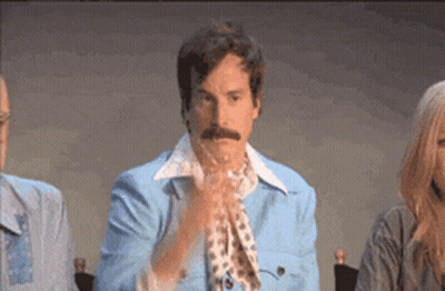 A Man With A Mustache Wearing A Blue Jacket And Scarf Is Clapping His Hands GIF