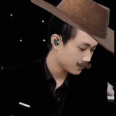 A Man With A Mustache Wearing A Cowboy Hat And Ear Buds GIF